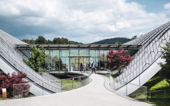 Eingang des Zentrum Paul Klee in Bern mit moderner Glas- und Wellenarchitektur, Besucherinnen und Besucher betreten das Museum.