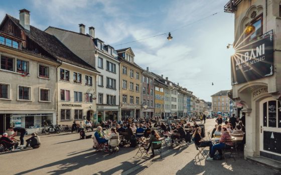 Lebendige Strassenszene in der Altstadt von Winterthur mit Menschen in Strassencafés vor historischen Häusern.