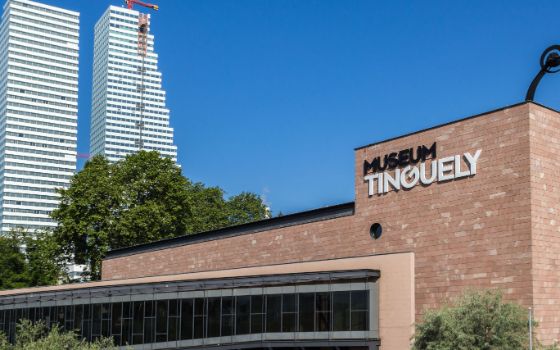 Fassade des Museum Tinguely in Basel mit moderner Architektur und Blick auf die Roche-Türme bei klarem Himmel.