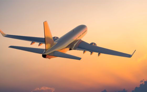 Passagierflugzeug im Sonnenuntergang, startet in den Urlaub, exklusive Reisen mit American Express Vorteilen.